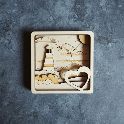 3D Multilayer-Bild Leuchtturm mit Herz aus Sperrholz, lasergraviert, Draufsicht auf grauem Untergrund